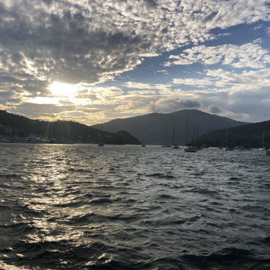 A picture of sailboats in Vathi's bay, sunsetting in the background.