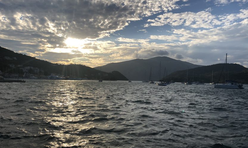 A picture of sailboats in Vathi's bay, sunsetting in the background.