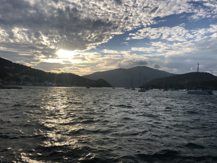 A picture of sailboats in Vathi's bay, sunsetting in the background.